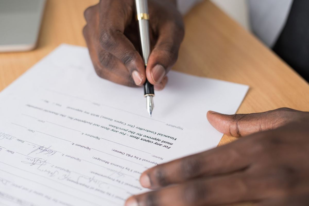 Mãos assinando um contrato sobre uma mesa