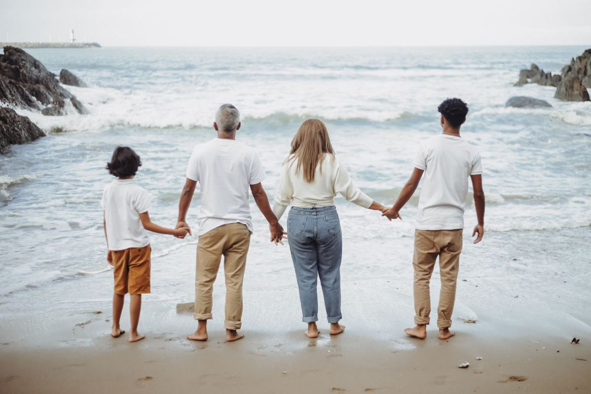 Família de mãos dadas à beira-mar, vista de costas